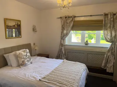 a bedroom with a bed with a window and a chandelier at Lulus in St Bees
