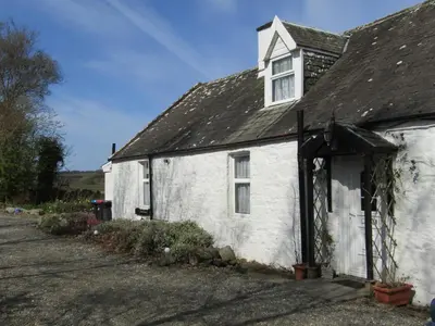 an old white house with a black roof at Barnkirk Holidays in Newton Stewart