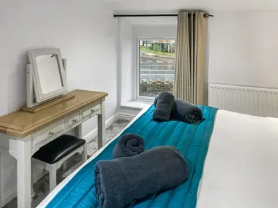 a bedroom with a bed with a desk and a mirror at Cosy Cottage in Portinscale