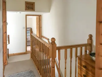 a staircase in a house with a wooden railing at Bay Cottage in Keswick