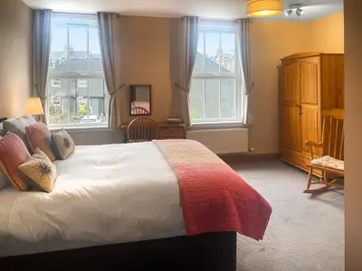 a bedroom with a large bed and two windows at Bay Cottage in Keswick