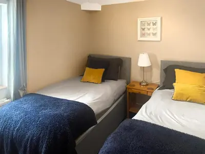 two beds in a small room with a blue blanket at Bay Cottage in Keswick
