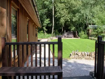 a wooden bench sitting on a porch with a yard at Rowanburn Lodge in Ellonby