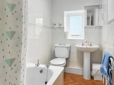 a white bathroom with a toilet and a sink at Ingle Neuk Cottage in Mosedale