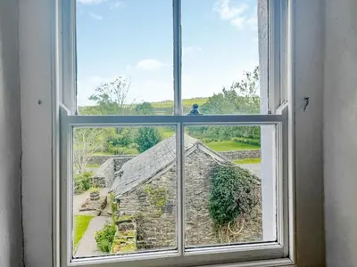 an open window with a view of a yard at Ingle Neuk Cottage in Mosedale
