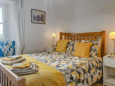 a bedroom with a large bed with yellow and orange pillows at Ingle Neuk Cottage in Mosedale