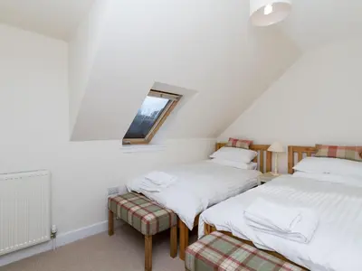 two twin beds in a room with a window at One The Stables in Dalrymple