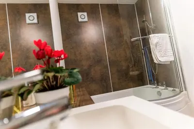 a bathroom with a sink and a shower with red flowers at Church View Irene Court Cockermouth in Cockermouth