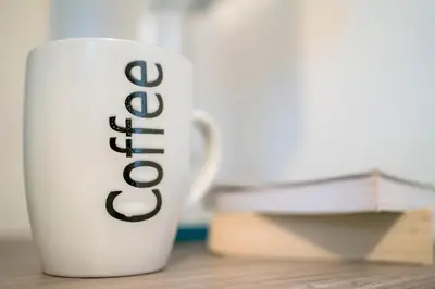 a white coffee cup sitting on a table next to books at Irene Court Cockermouth in Cockermouth