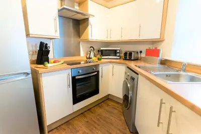a kitchen with white cabinets and a dishwasher at Irene Court Cockermouth in Cockermouth