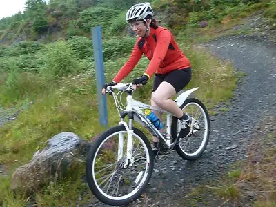 a woman riding a bike on a dirt road at Culsharg Cottage in Bargrennan