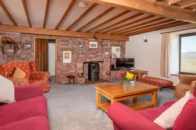 a living room with couches and a brick fireplace at Saddleback Barn in Penrith