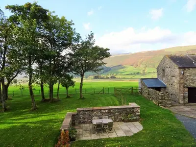 a stone building with a table and chairs in a field at Sharp Edge in Penrith