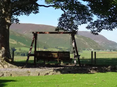 a wooden swing under a tree in a field at Sharp Edge in Penrith