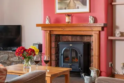 a living room with a fireplace and a table with wine glasses at Stable Barn in Penrith