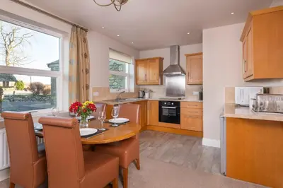 a kitchen with a wooden table with chairs and a dining room at Bannerdale in Penrith