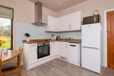 a kitchen with white cabinets and a table and a refrigerator at Grisdale View in Penrith
