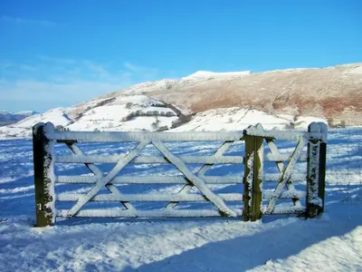 a gate in the snow with a mountain in the background at Howe Top in Mungrisdale