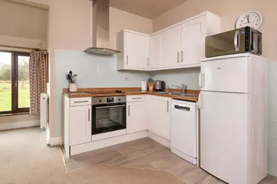 a kitchen with white cabinets and a white refrigerator at Howe Top in Mungrisdale
