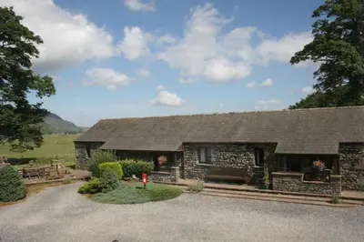 a stone house with a gravel driveway at Howe End in Mungrisdale