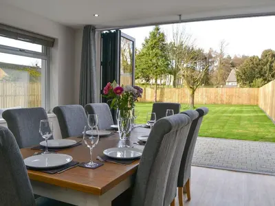 a dining room table with chairs and a large window at Ancrum House in Gretna Green