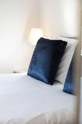 a bed with blue and white pillows and a blue pillow at The Original Donnini Apartment in Ayr