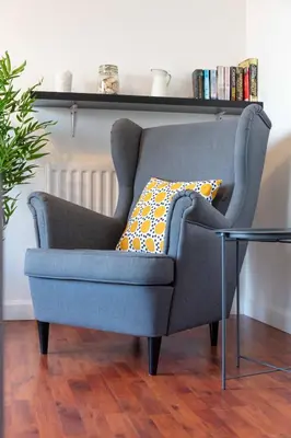 a blue chair sitting in a living room with a table at The Original Donnini Apartment in Ayr