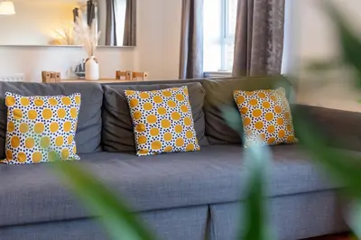 a blue couch with yellow and white pillows on it at The Original Donnini Apartment in Ayr