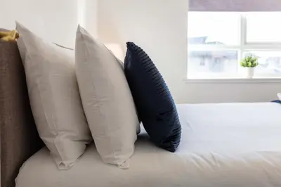 two pillows sitting on a bed with a window at The Original Donnini Apartment in Ayr