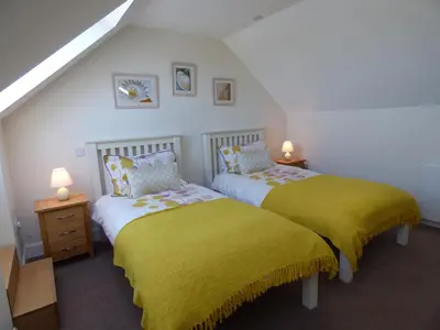 two beds in a room with yellow blankets and lamps at Cairndoon Byre in Monreith