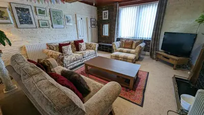 a living room with couches and a flat screen tv at The Mansion in Whitehaven