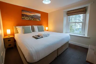 a bedroom with a large white bed with an orange wall at Royal Hotel in Dockray