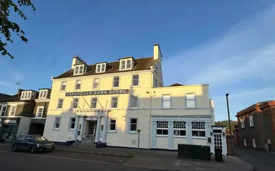 a white building with a car parked in front of it at Annandale Arms Hotel in Moffat