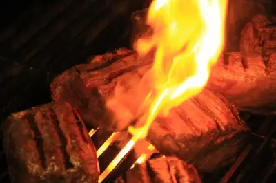a piece of meat cooking on a grill with flames at Annandale Arms Hotel in Moffat