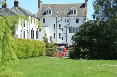 a large white building with a grass yard in front of it at Annandale Arms Hotel in Moffat