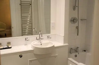 a white bathroom with a sink and a shower at Annandale Arms Hotel in Moffat