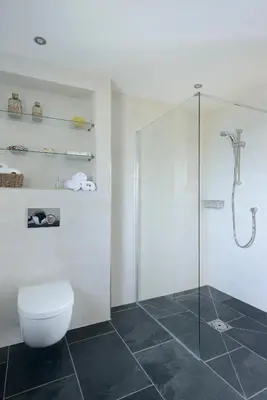 a bathroom with a toilet and a glass shower at Airds Bay Luxury Beach House in Gatehouse of Fleet