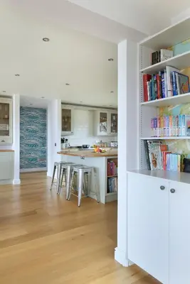 a white kitchen with a table and chairs and books at Airds Bay Luxury Beach House in Gatehouse of Fleet