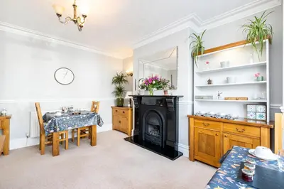 a living room with a table and a fireplace at Cragwood Guest House in Keswick