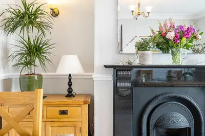 a living room with a fireplace with flowers on top at Cragwood Guest House in Keswick