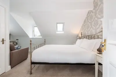 a bedroom with a white bed with a wooden headboard at Cragwood Guest House in Keswick