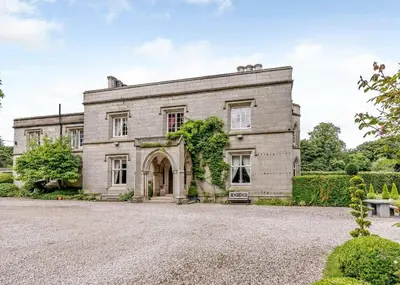 an old stone house with a driveway at Calthwaite Hall Lodges in Calthwaite