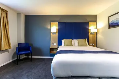 a bedroom with a large bed and a blue wall at Days Inn Hotel Gretna Green in Gretna Green