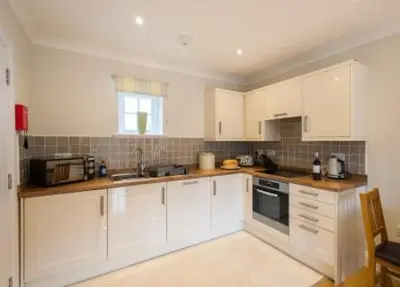 a white kitchen with white cabinets and a window at Milntown Self Catering Apartments in Ramsey