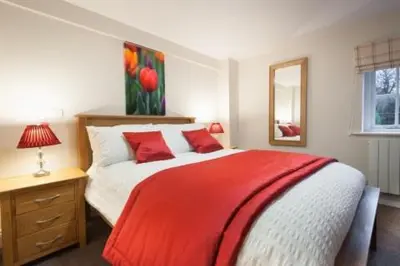 a bedroom with a large bed with a red blanket at Milntown Self Catering Apartments in Ramsey