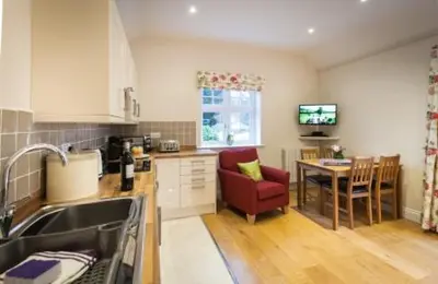 a kitchen with a sink and a table with a red chair at Milntown Self Catering Apartments in Ramsey