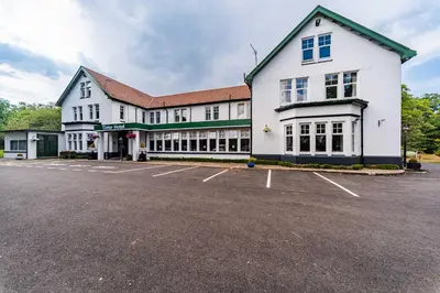 a large white building with a parking lot at Tinto Hotel in Symington
