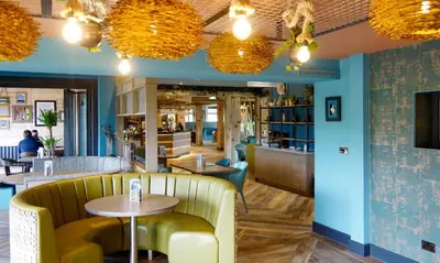 a restaurant with a yellow couch and tables and chairs at The Gailes Hotel & Spa in Irvine
