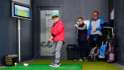a young boy is playing golf with his family at The Gailes Hotel & Spa in Irvine