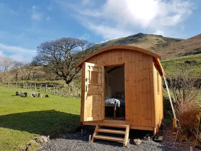 a wooden out house with a ladder in a field at Stybeck Farm Shephards Hut in Thirlmere